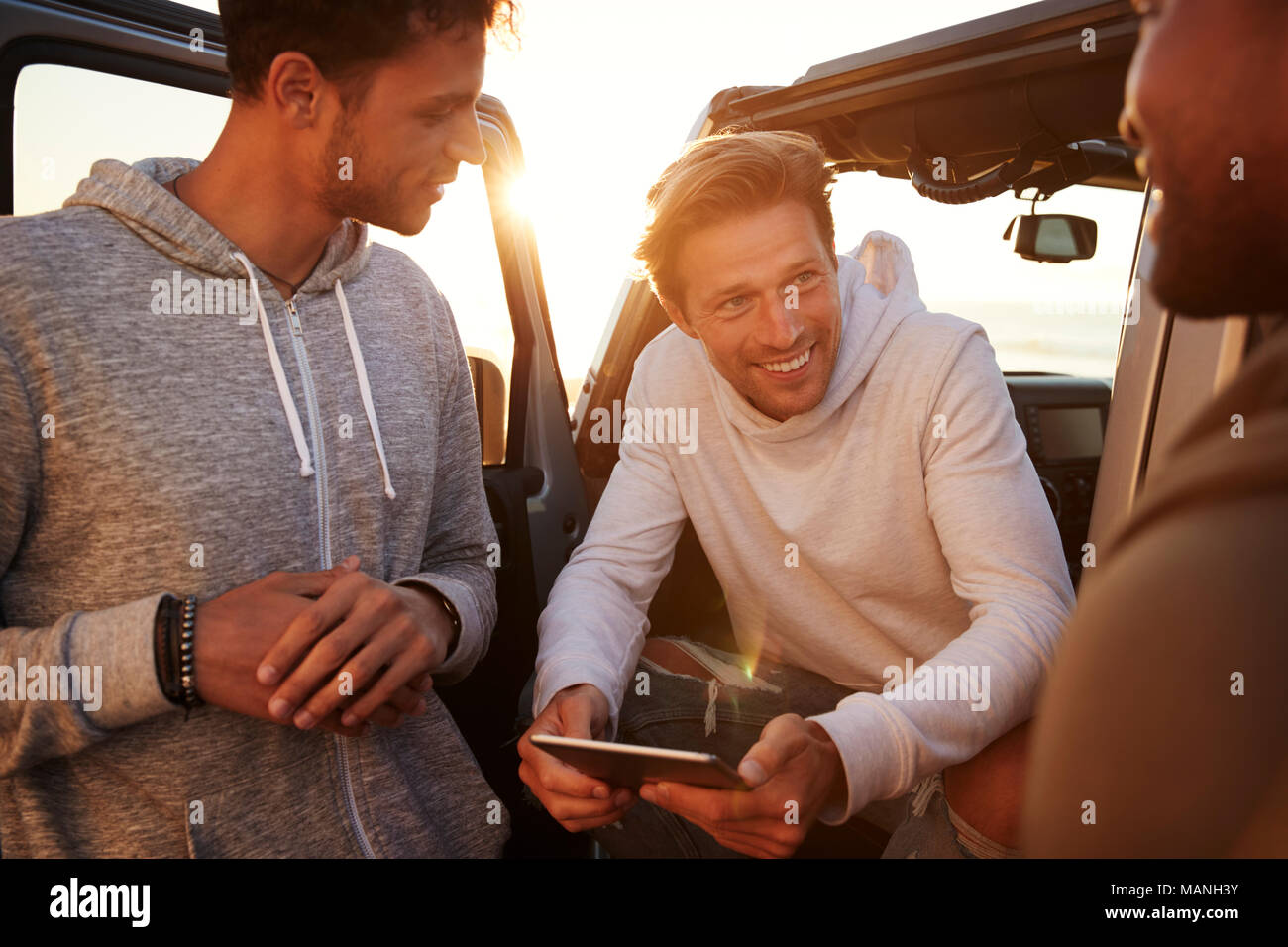 Three male friends on a road trip using a tablet, close up Stock Photo