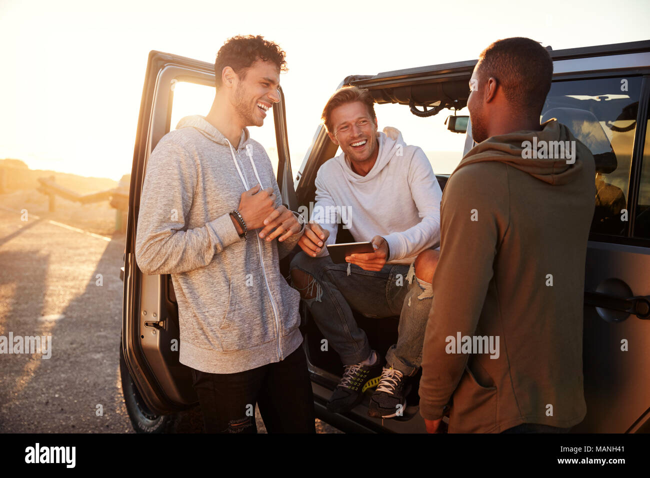 Three male friends on a road trip using a tablet computer Stock Photo