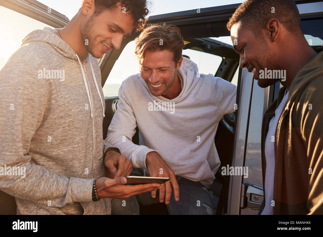 Male friends planning road trip route with tablet computer Stock Photo