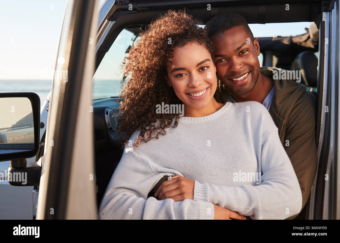 Young mixed race couple embracing by car, close up Stock Photo