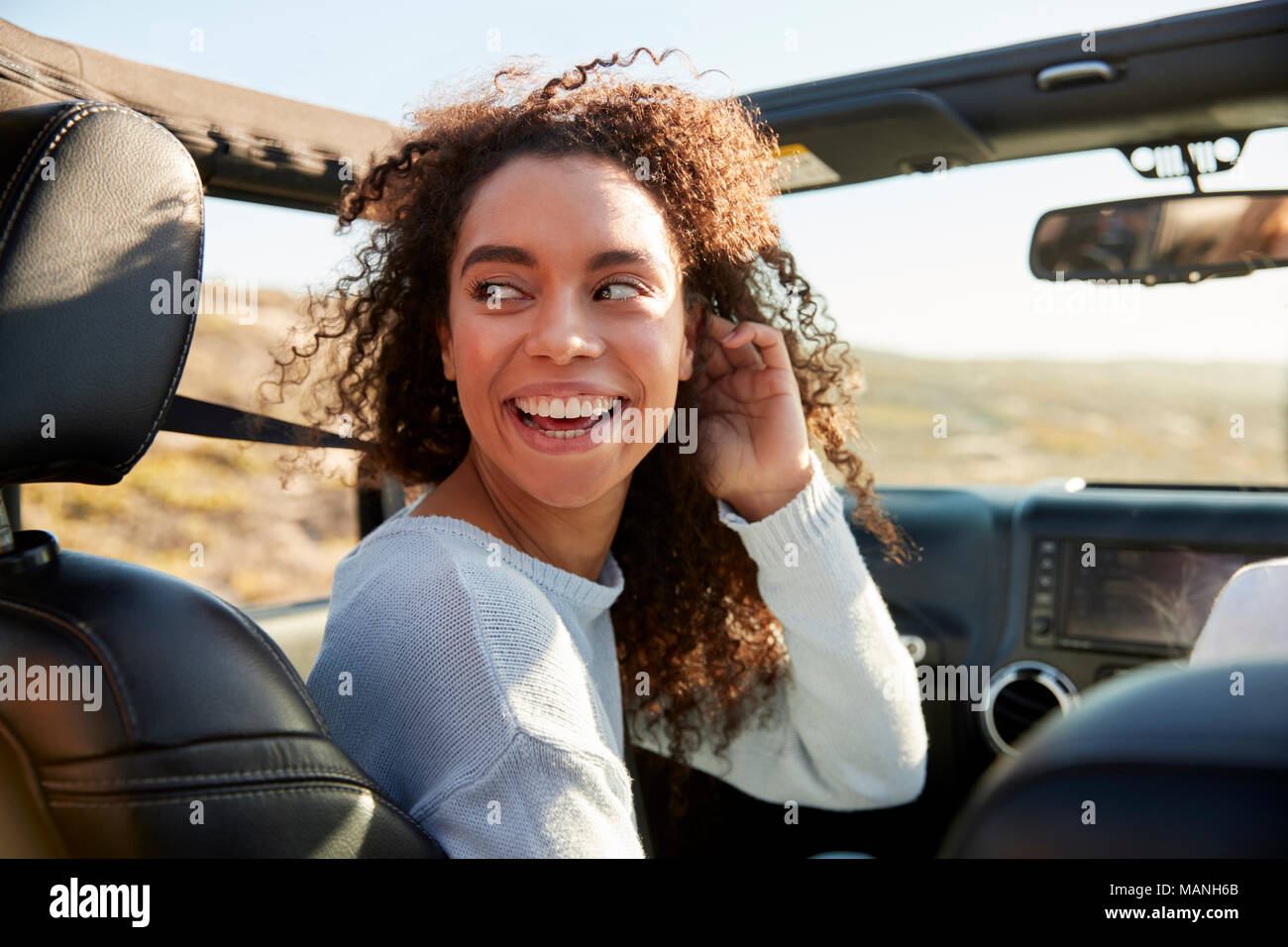 Young woman turning round in front passenger seat of a car Stock Photo