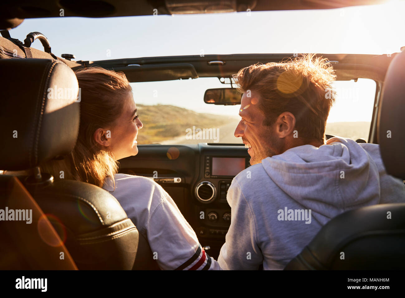 Couple look at each other while driving, rear passenger POV Stock Photo