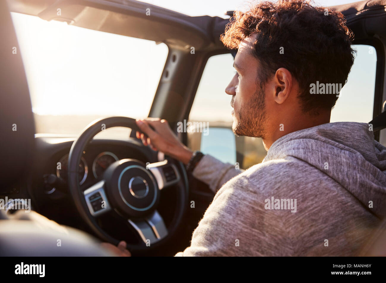 Side view of young Hispanic man driving with sunroof open Stock Photo