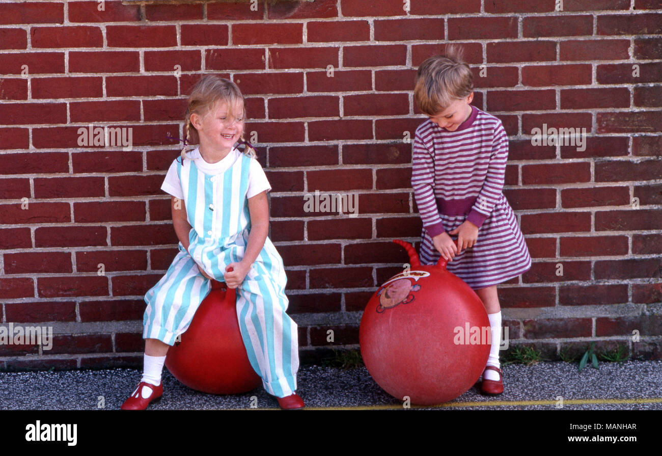 Girls playing on bouncy ball with handles Stock Photo
