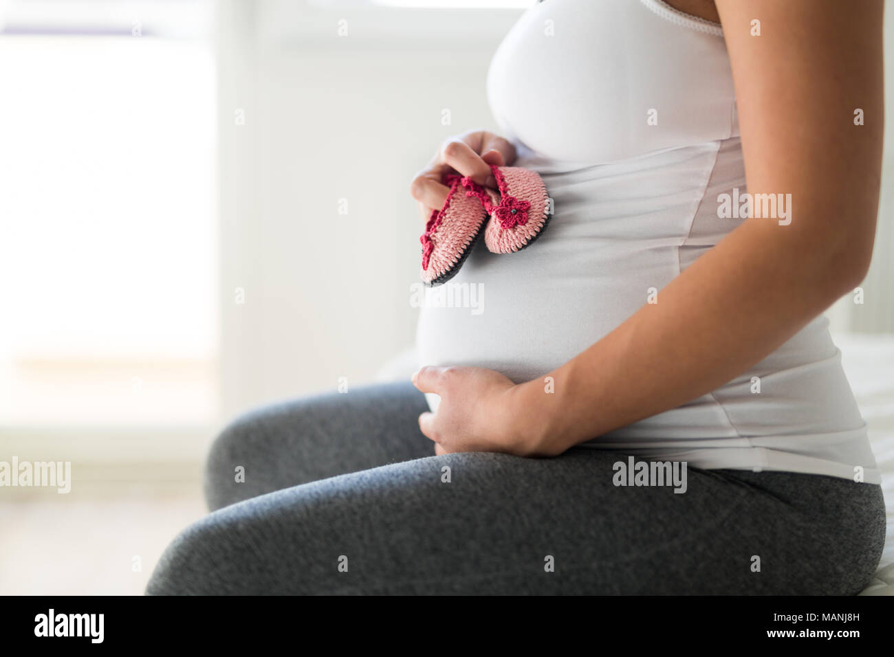 Pregnant woman holding baby shoes on her belly Stock Photo