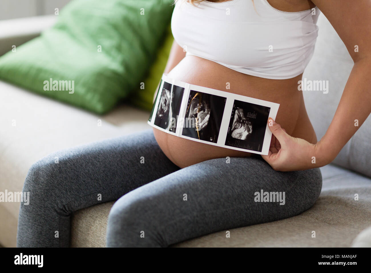 Pregnant woman holding ultrasound photo on belly Stock Photo - Alamy
