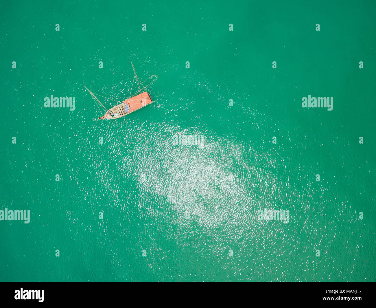 Dropshot of fishing boat on emerald tropical sea Stock Photo