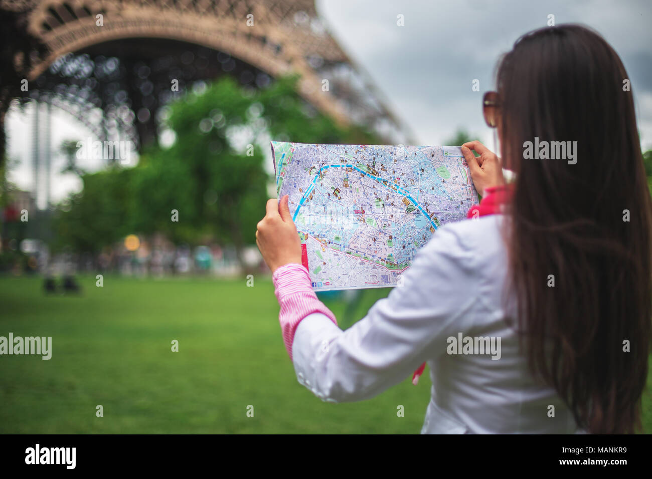 Confused young girl holding city Maps in Tuileries garden Paris, France Stock Photo