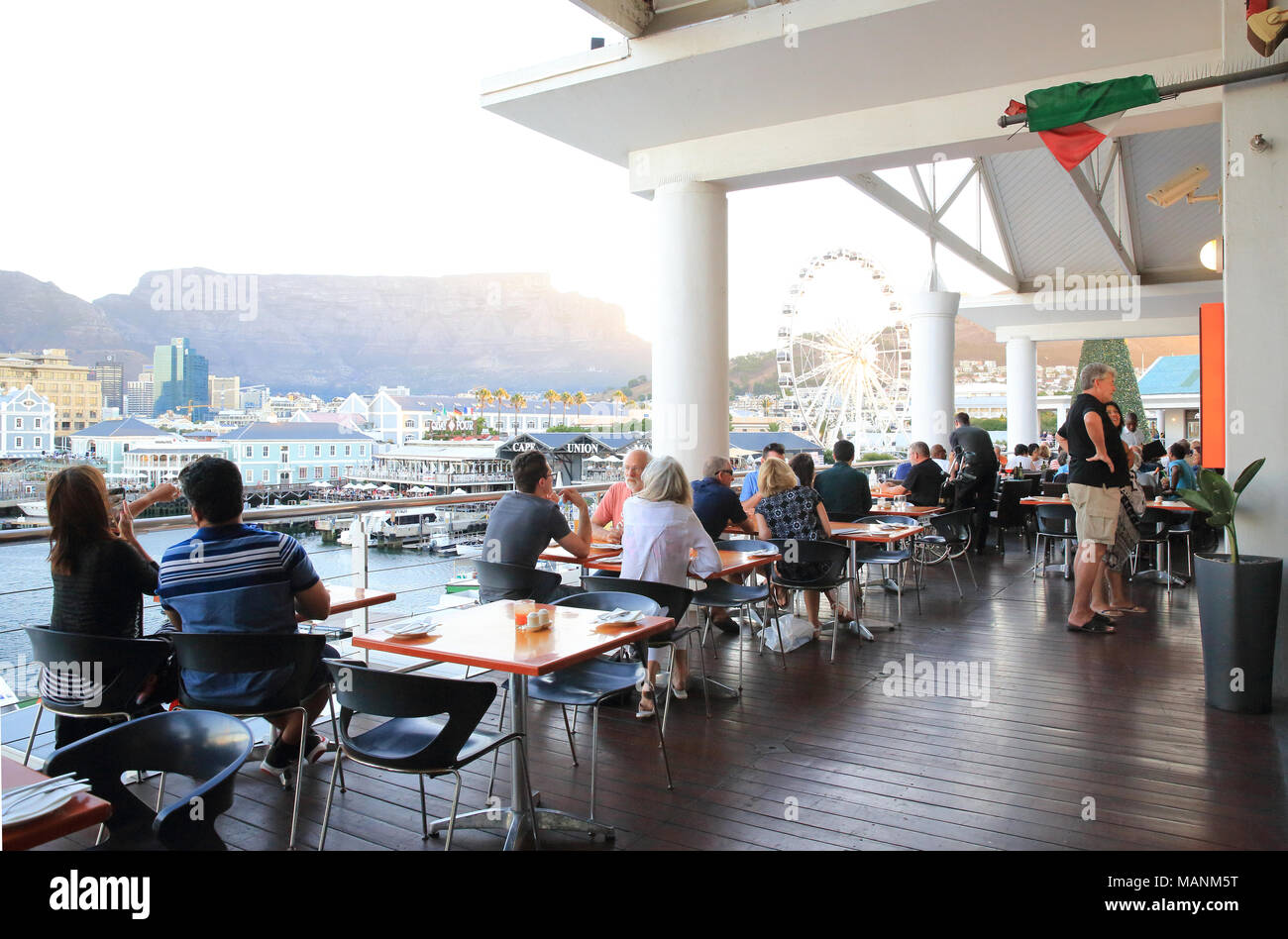People eating in restaurants overlooking the V&A Waterfront at dusk, in