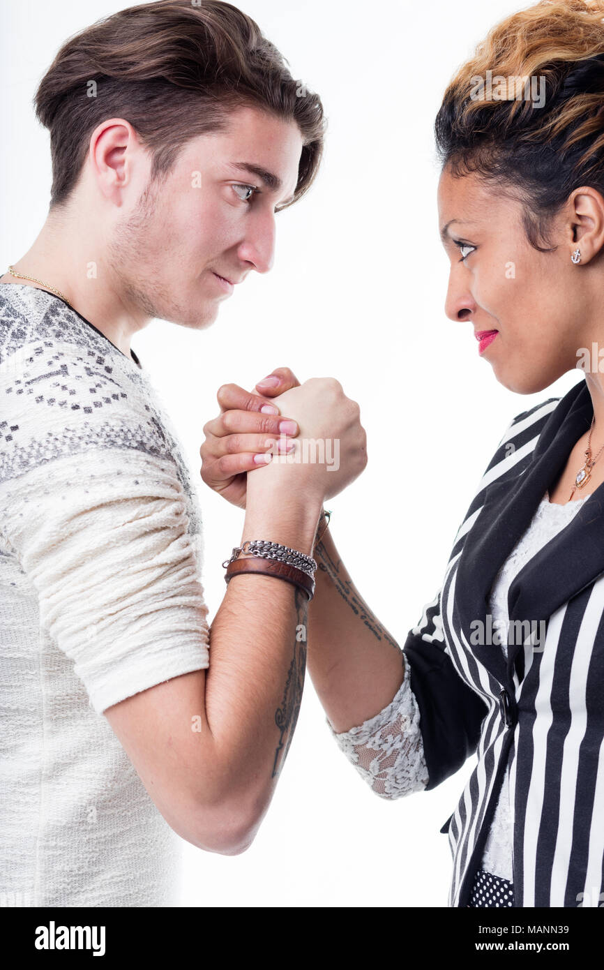 Man and woman facing off in a battle of wills and strength arm wrestling face to face with determined looks isolated on white Stock Photo