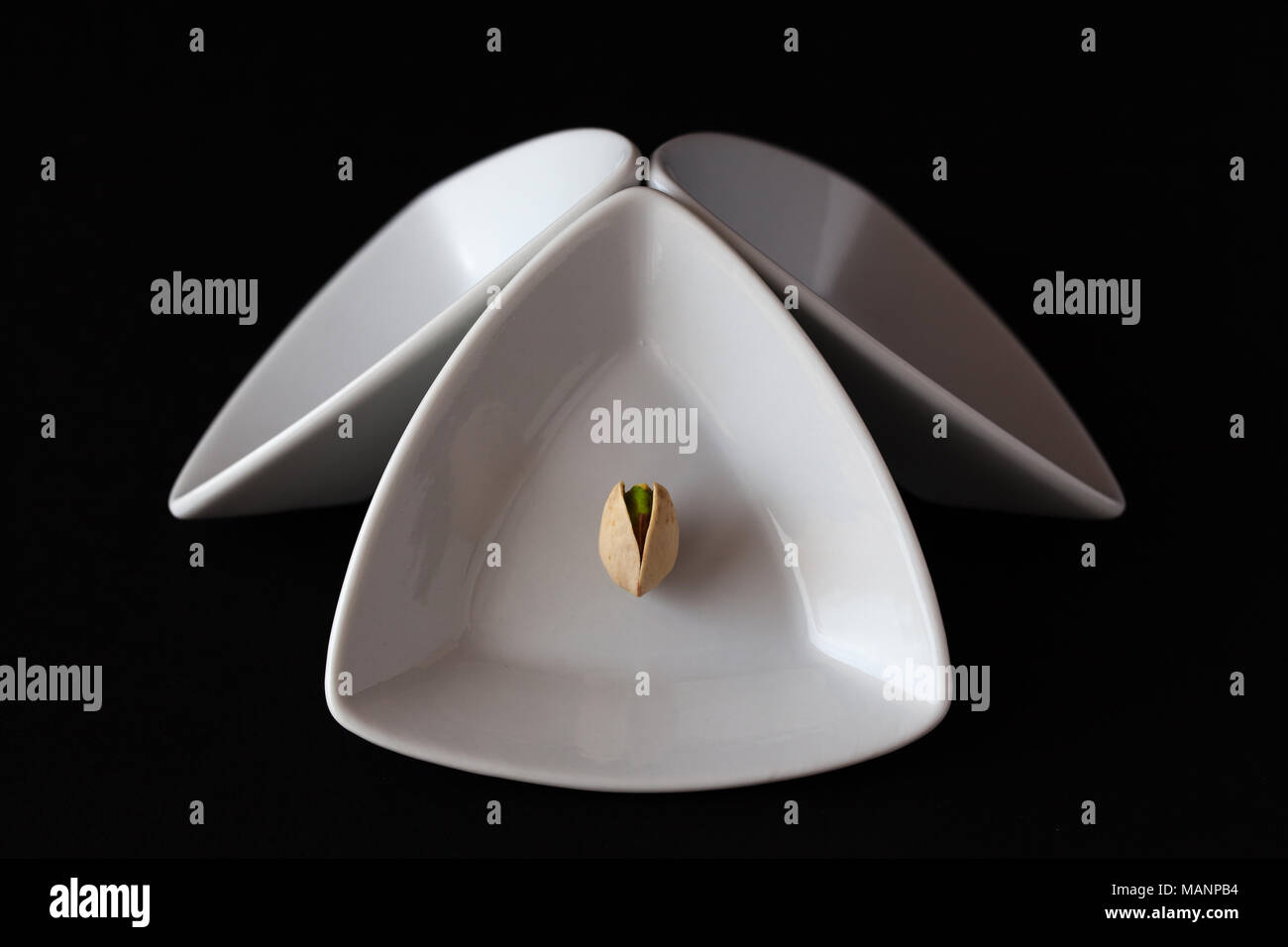 White triangular ceramic bowls with pistachio nut on the black background. Dark Food Photography