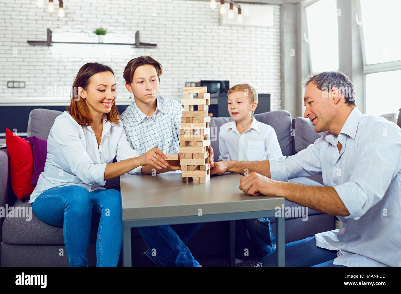 The family plays board games inside the room. Stock Photo