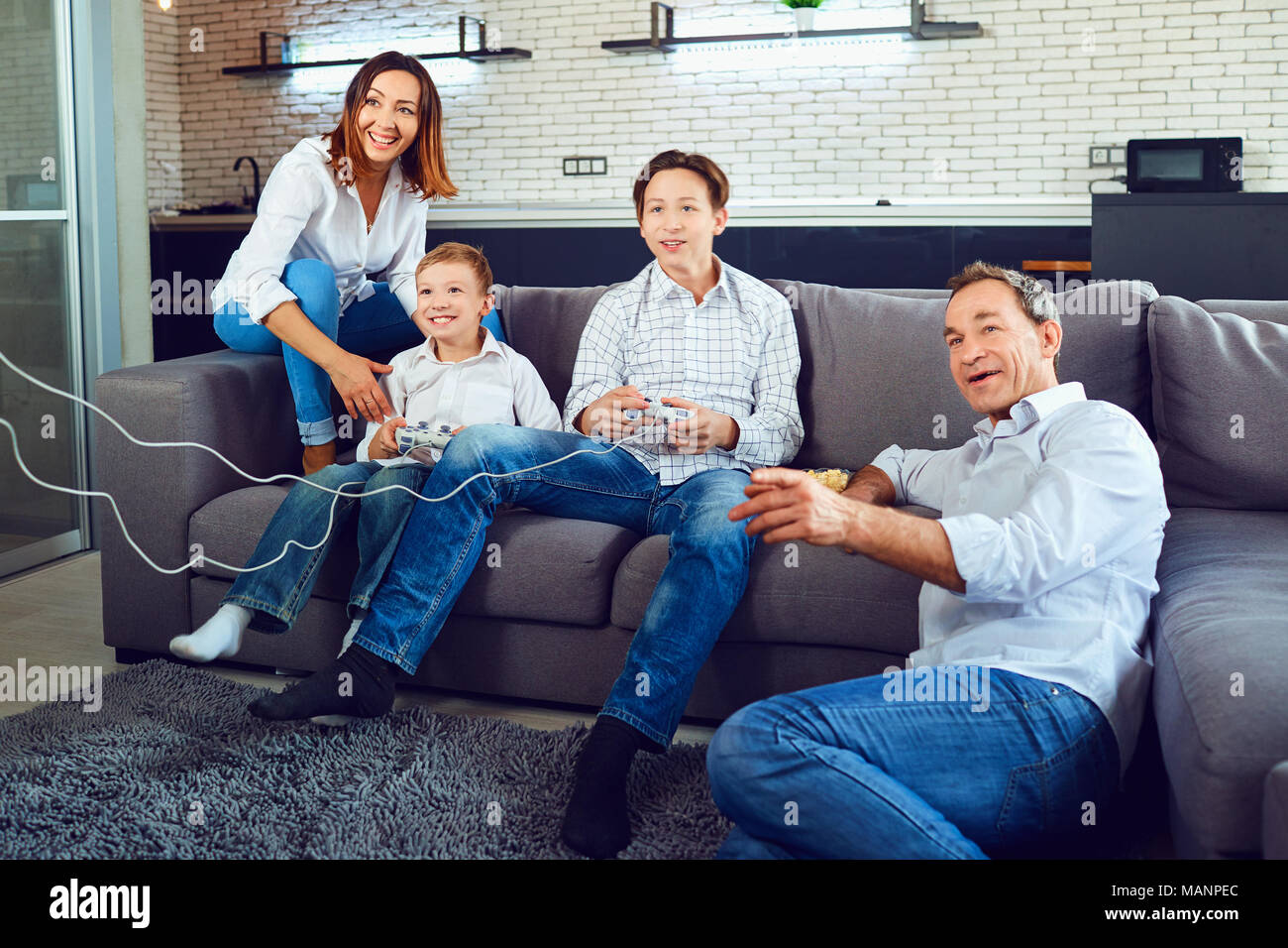 A cheerful family is playing video games while sitting on a sofa Stock Photo