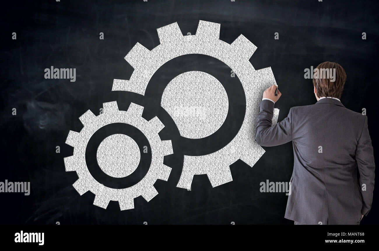 Businessman painting gear icon on blackboard concept. Stock Photo
