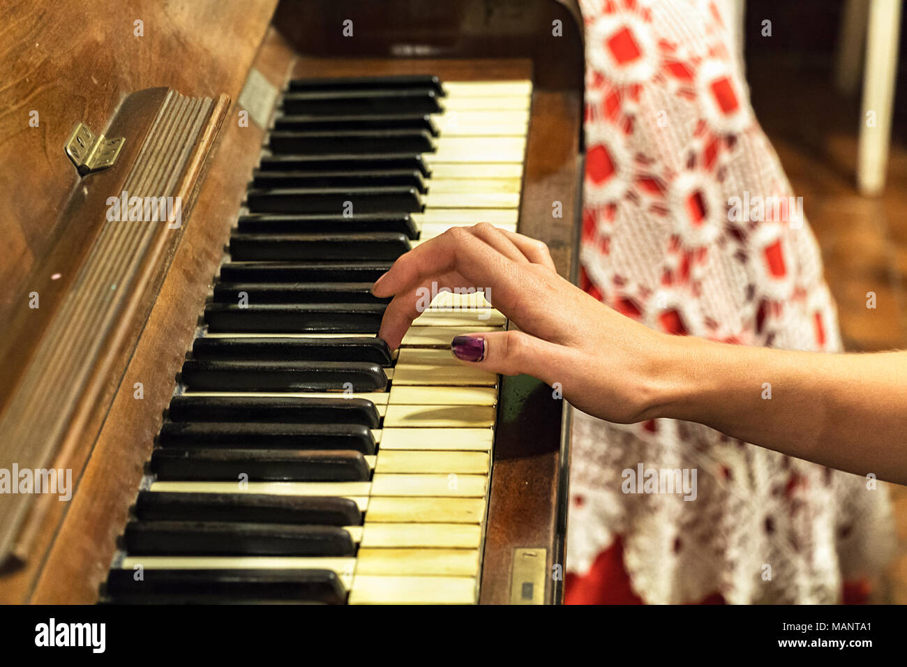 A hand of a female young woman with colored nails playing a very old