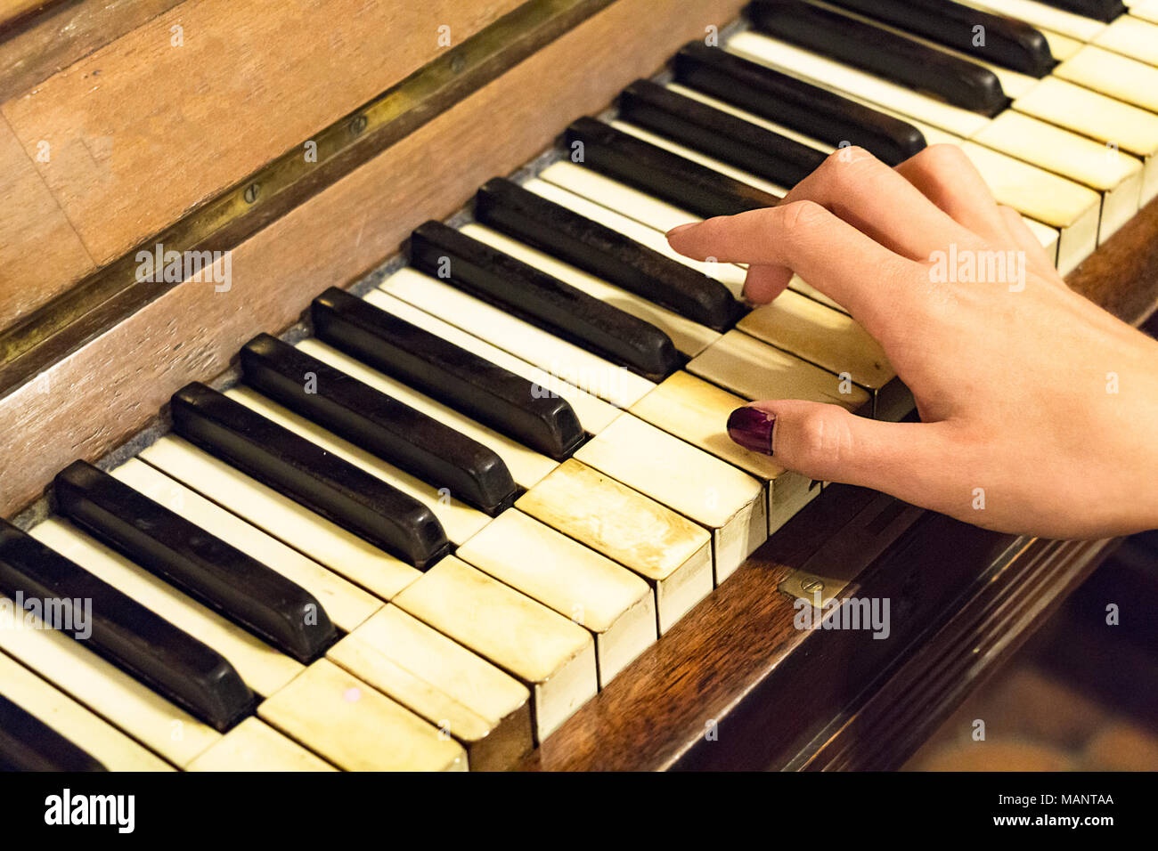A hand of a female young woman with colored nails playing a very old