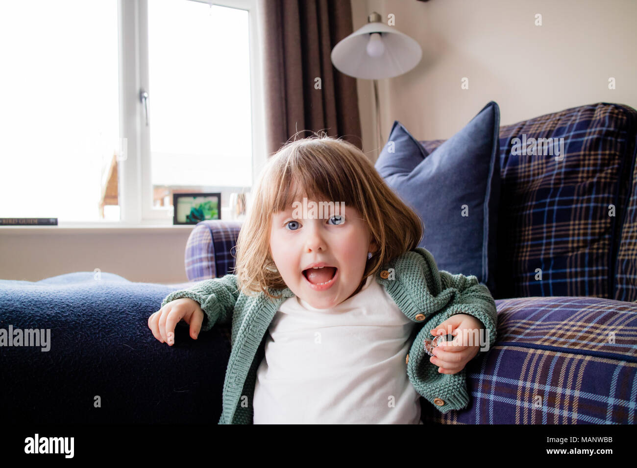 A young girl screaming at the camera in the house. Stock Photo