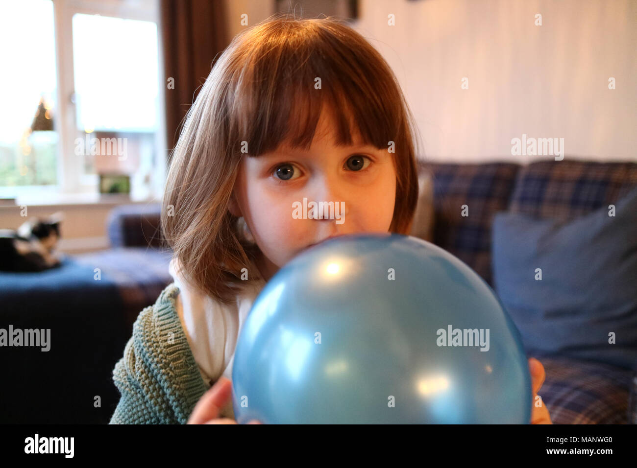 A shy young girl hiding behind a balloon, while looking into the camera  Stock Photo - Alamy