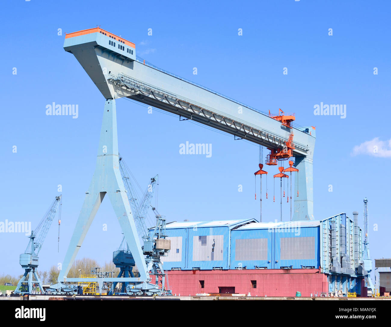 Container harbor with harbor cranes or freight cranes. Warf or cargo shipping scene, industrial transportation or shipping scene. Hamburg harbor. Stock Photo