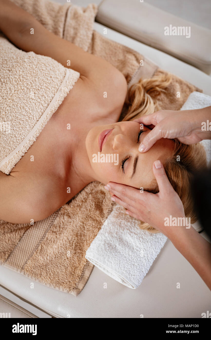 Close-up of a beautiful healthy young woman enjoying relaxing facial massage at beauty salon. Top view. Stock Photo