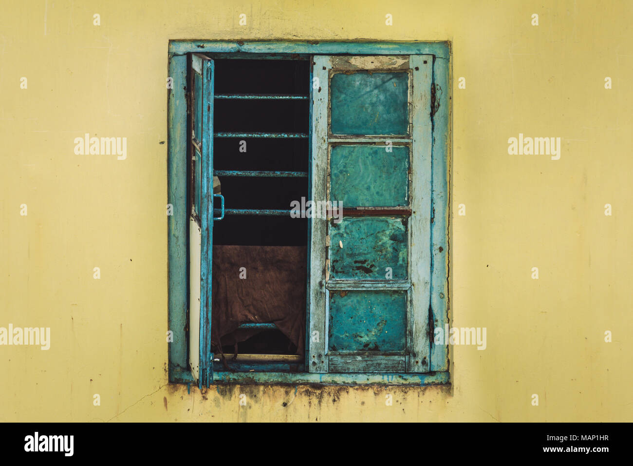 Open Old Window On yellow Wall. window with metal grating Stock Photo