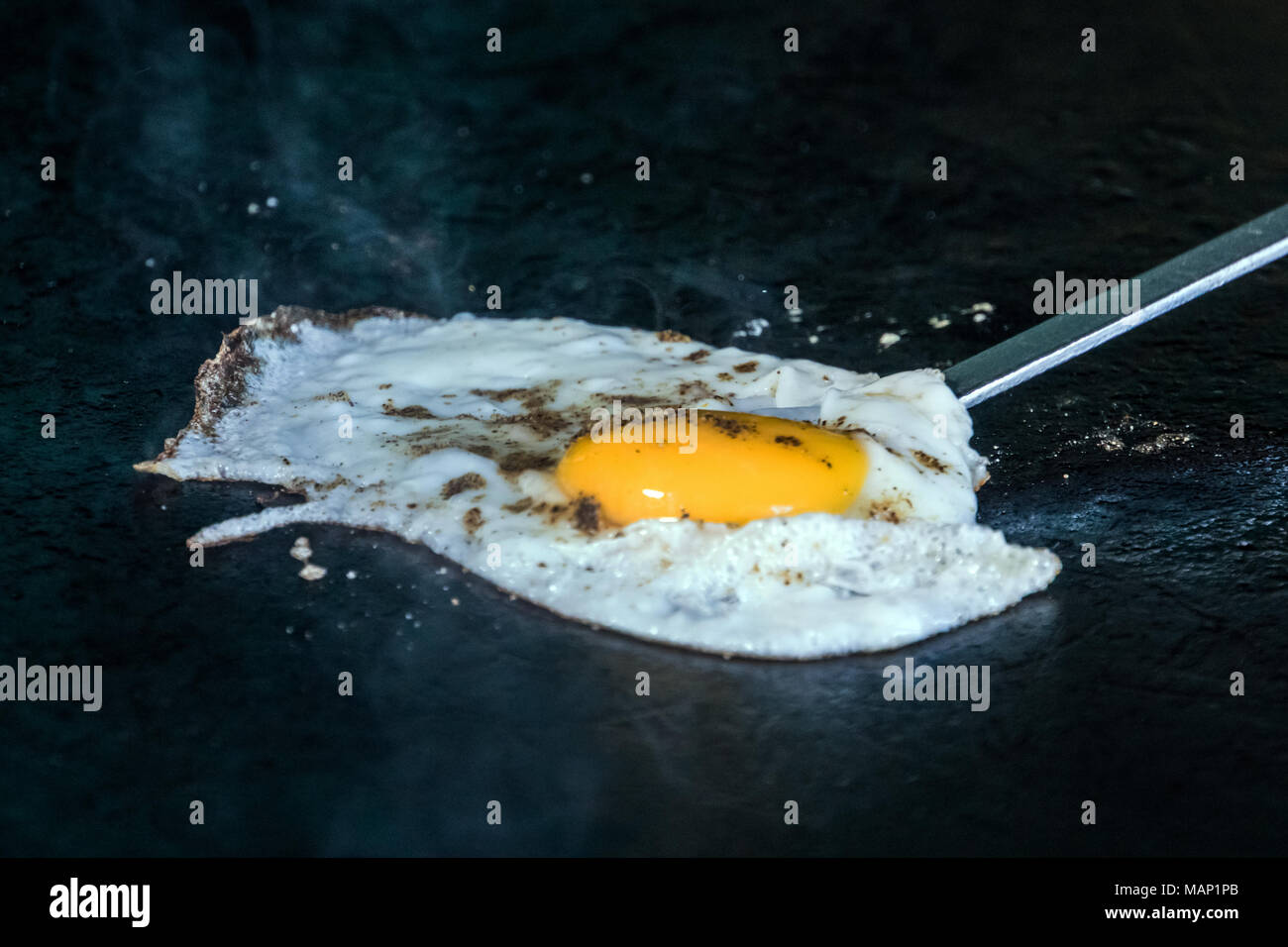 one fried egg. cook removes from the pan fried egg seasoned with spices, soft-boiled egg Stock Photo