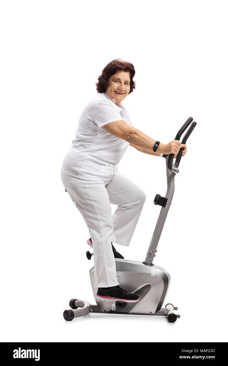 Elderly woman exercising on a stationary bike and looking at the camera  isolated on white background Stock Photo - Alamy