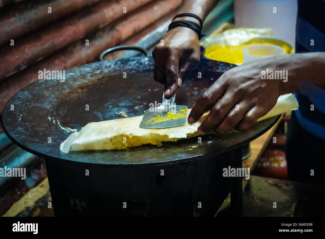 chicken and egg kathi rolls with onions being prepared on a black surface with green limes by a street food vendor in Kolkata, West Bengal, India. uns Stock Photo