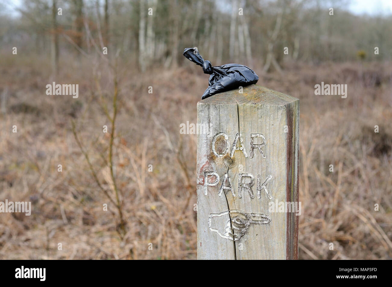 Dog poo bag left on wooden sign post Stock Photo