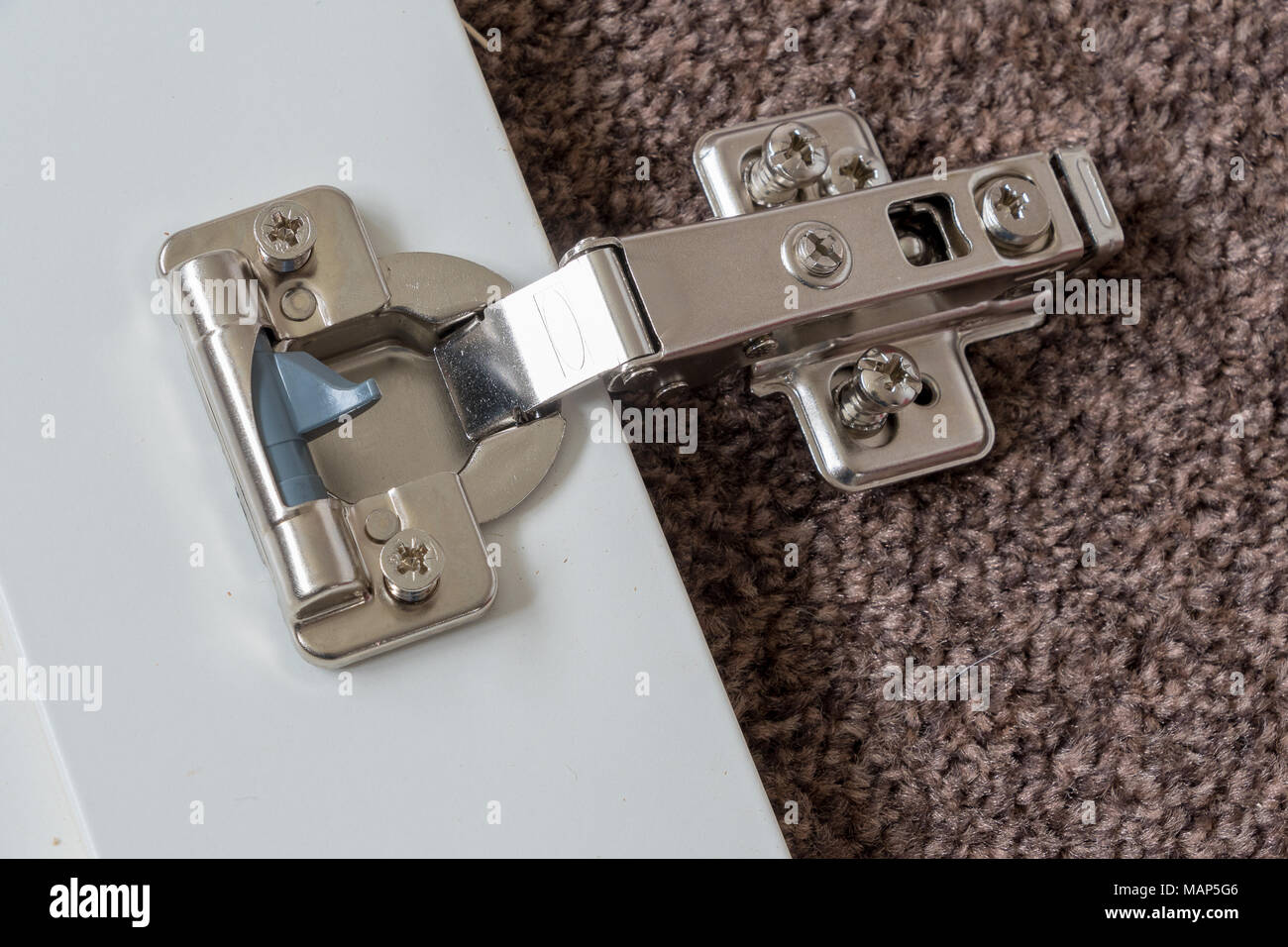 A soft closing door hingle being fitted to flat pack furniture. Stock Photo