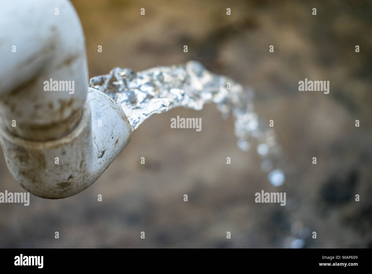 freezing motion of water flow from a plastic tap and falling down to the floor Stock Photo