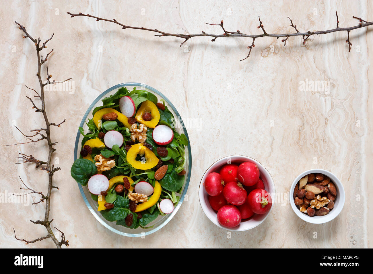 Healthy vegan salad with radish, nuts, yellow pepper on marble with copy space Stock Photo