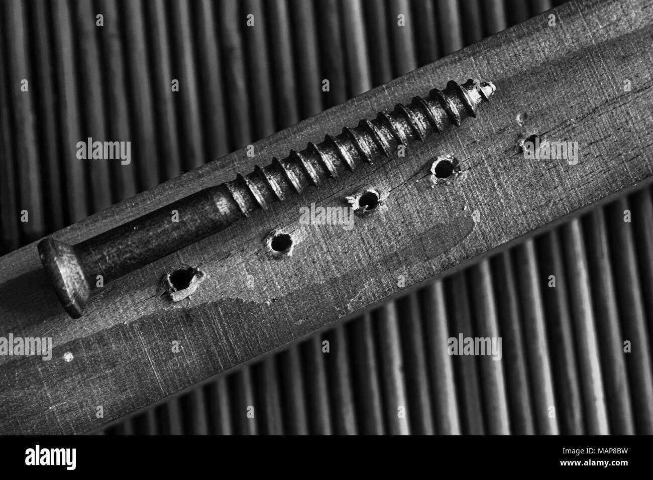 Monochrome wooden planks with holes and screw isolated on bamboo background. Stock Photo