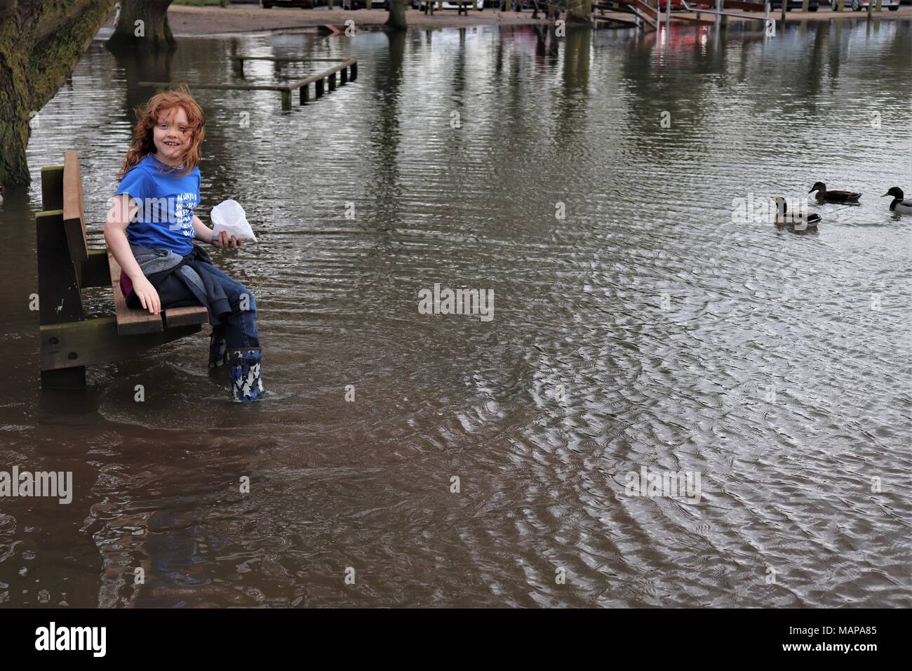 A young Ginger Haired girl in a blue top has fun in a flooded park Stock Photo