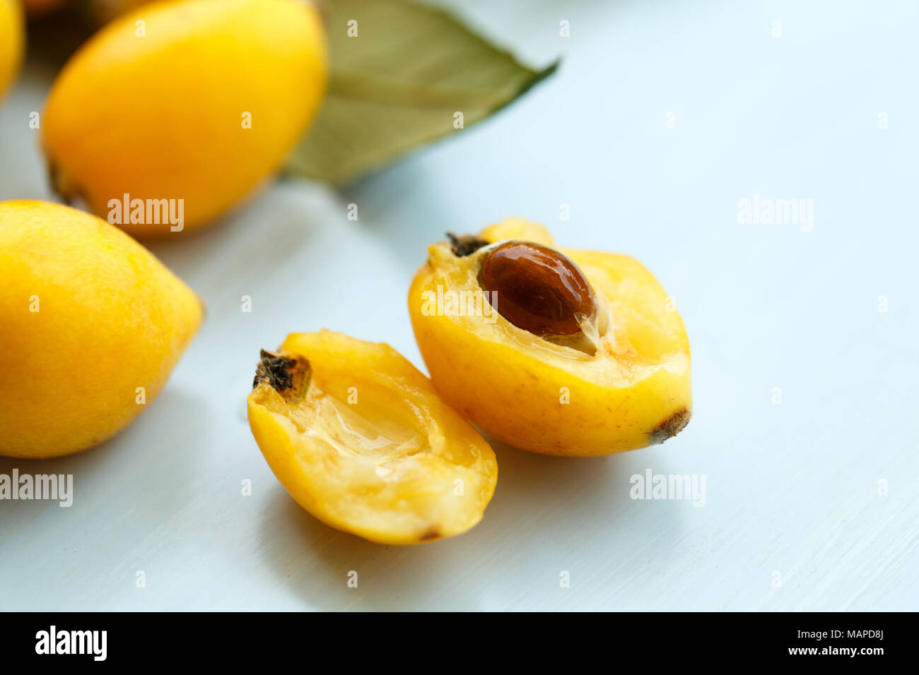 Loquat orange fruits on branch with leaves on a blue wooden background Stock Photo