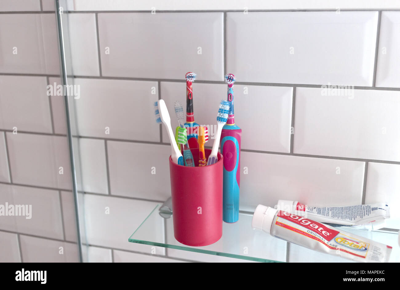 A variety of toothbrushes, including electric toothbrushes in a bathroom setting Stock Photo