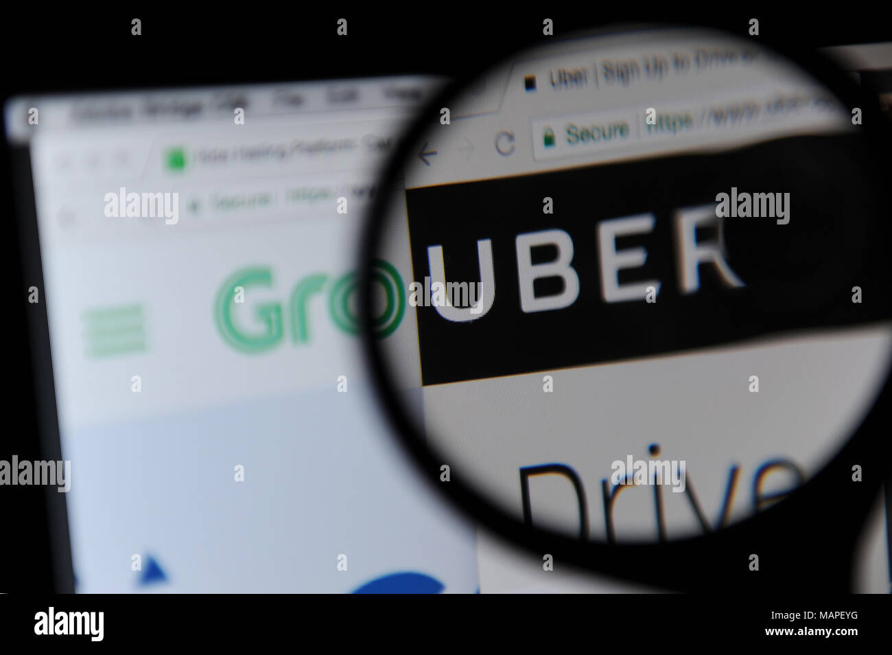 Ride sharing websites, Grab and Uber webpages are both seen on a computer screen Stock Photo