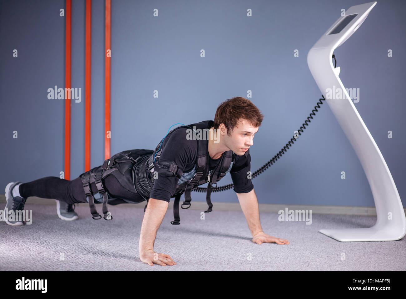 man in Electrical Muscular Stimulation suits doing plank exercise. EMS