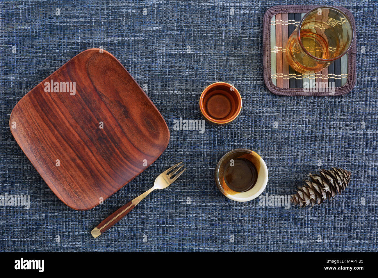 Wooden plate, wood and brass fork, amber glass and brown condiment pots