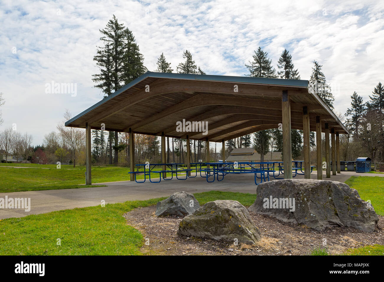 Picnic tables under wood shelter structure in suburban neighborhood city park Stock Photo