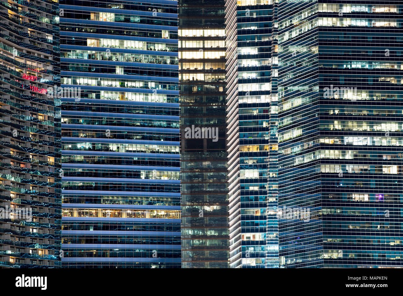 Glass facade of modern city high rise, buildings show lighting using by human activity, energy usage at night time. Stock Photo