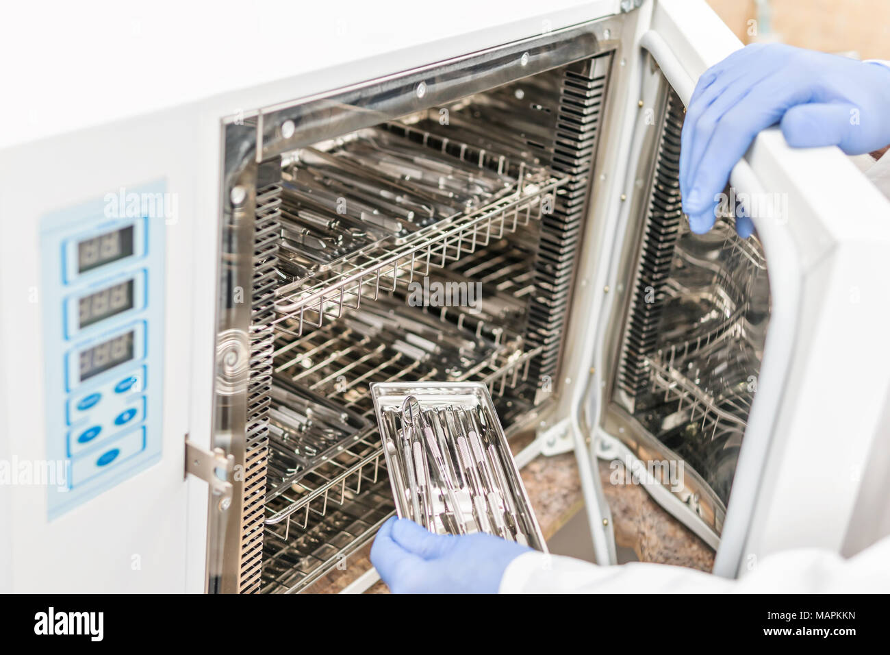 Dentist opened the door of the sterilization autoclave and loads the