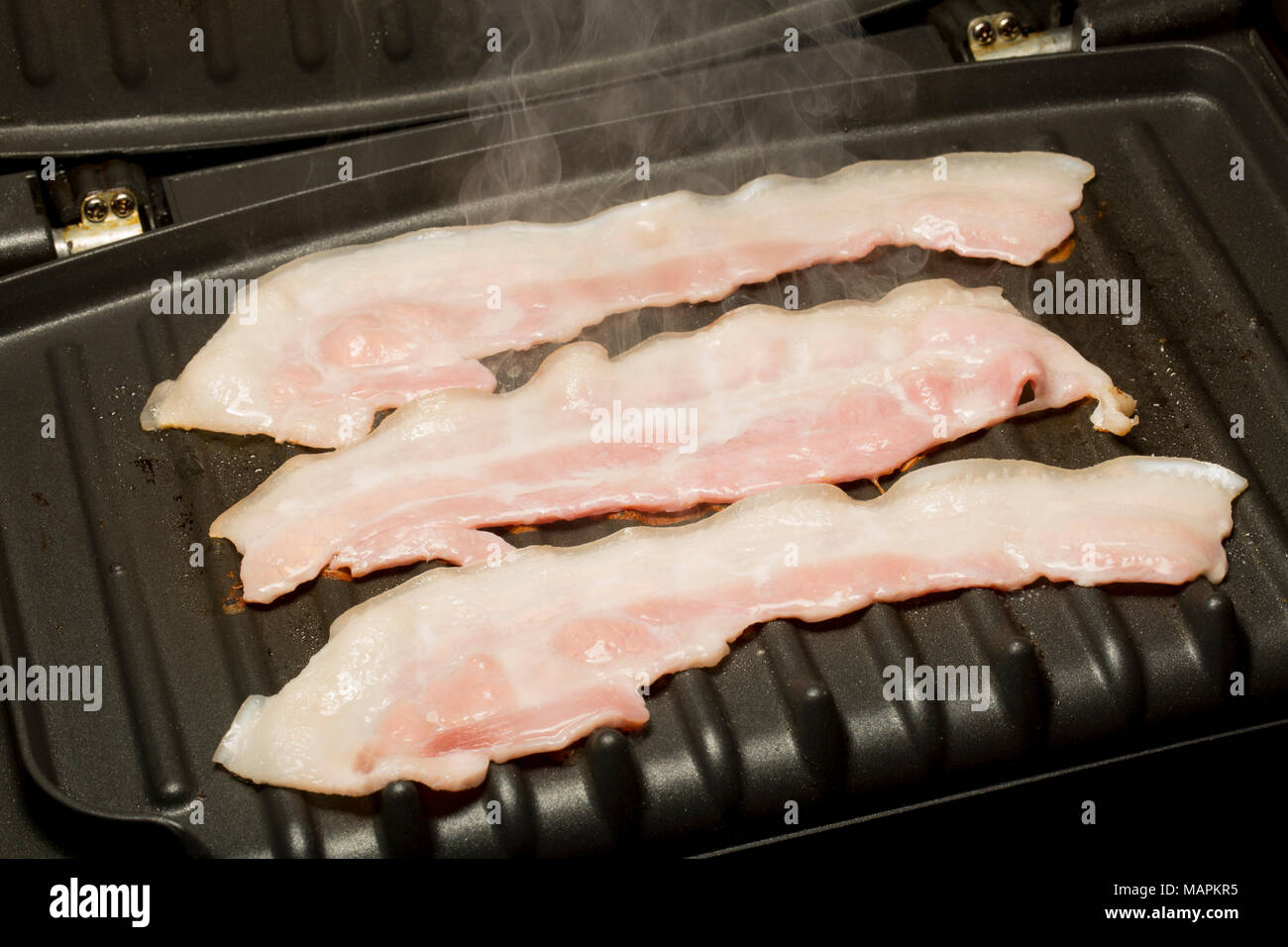 Streaky, unsmoked EU bacon from a supermarket fried on a George Foreman Fat  Reducing Grill using the natural fat of the bacon. UK Stock Photo - Alamy