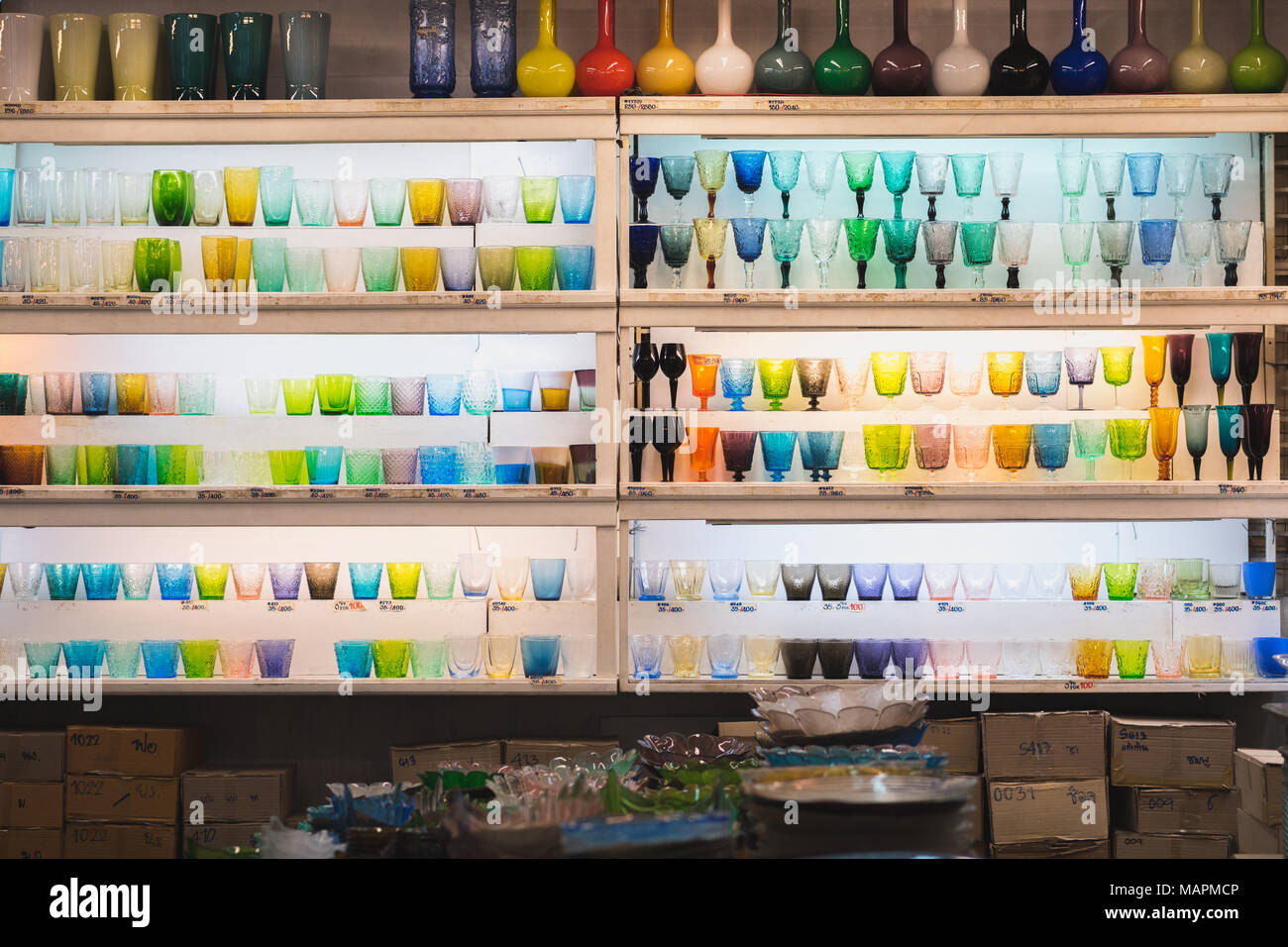 Shelves with multi-colored glasses at dishes shop in Chatuchak weekend market. Chatuchak market is a famous shopping area in Bangkok Stock Photo