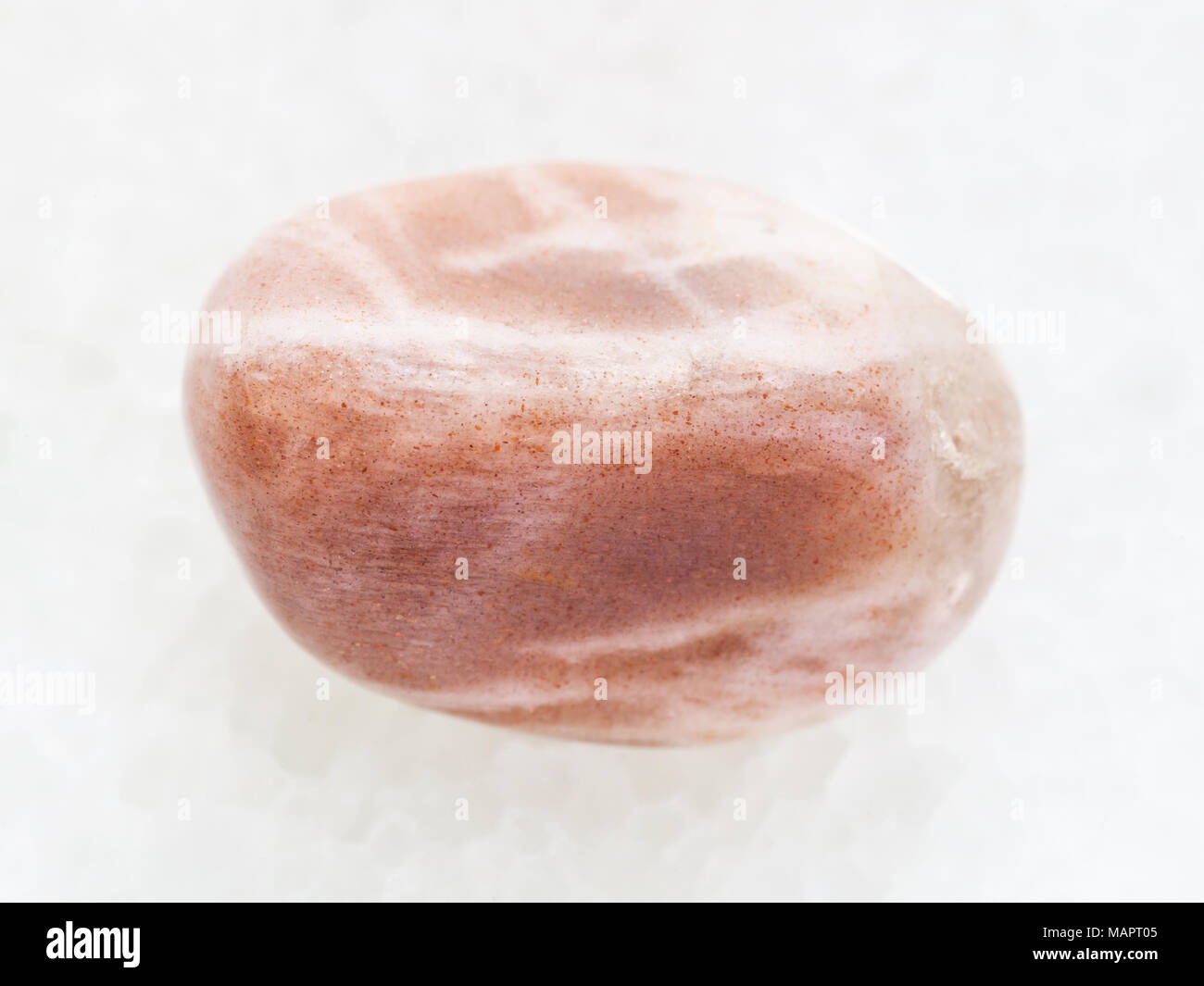 macro shooting of natural mineral rock specimen - tumbled moonstone gemstone on white marble background Stock Photo