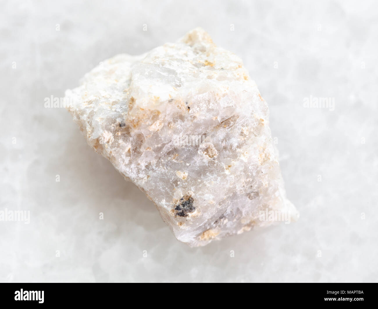 macro shooting of natural mineral rock specimen - raw Conglomerate stone on white marble background Stock Photo
