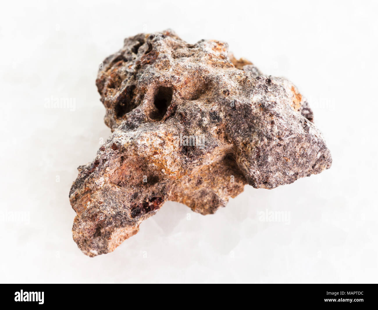 macro shooting of natural mineral rock specimen - raw Basalt stone on white marble background Stock Photo