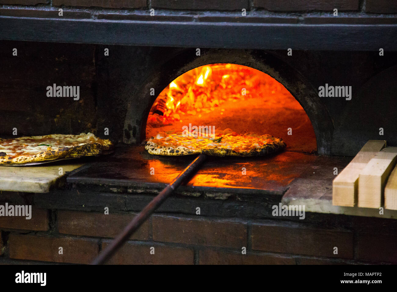 Pizza coming out of the wood-fired oven at the famous L'Antica Pizzeria Da Michele in Naples, Italy Stock Photo