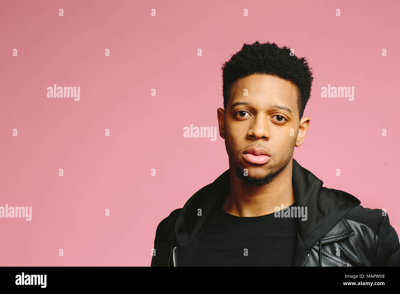 Portrait of a serious young man, isolated on pink studio background Stock Photo