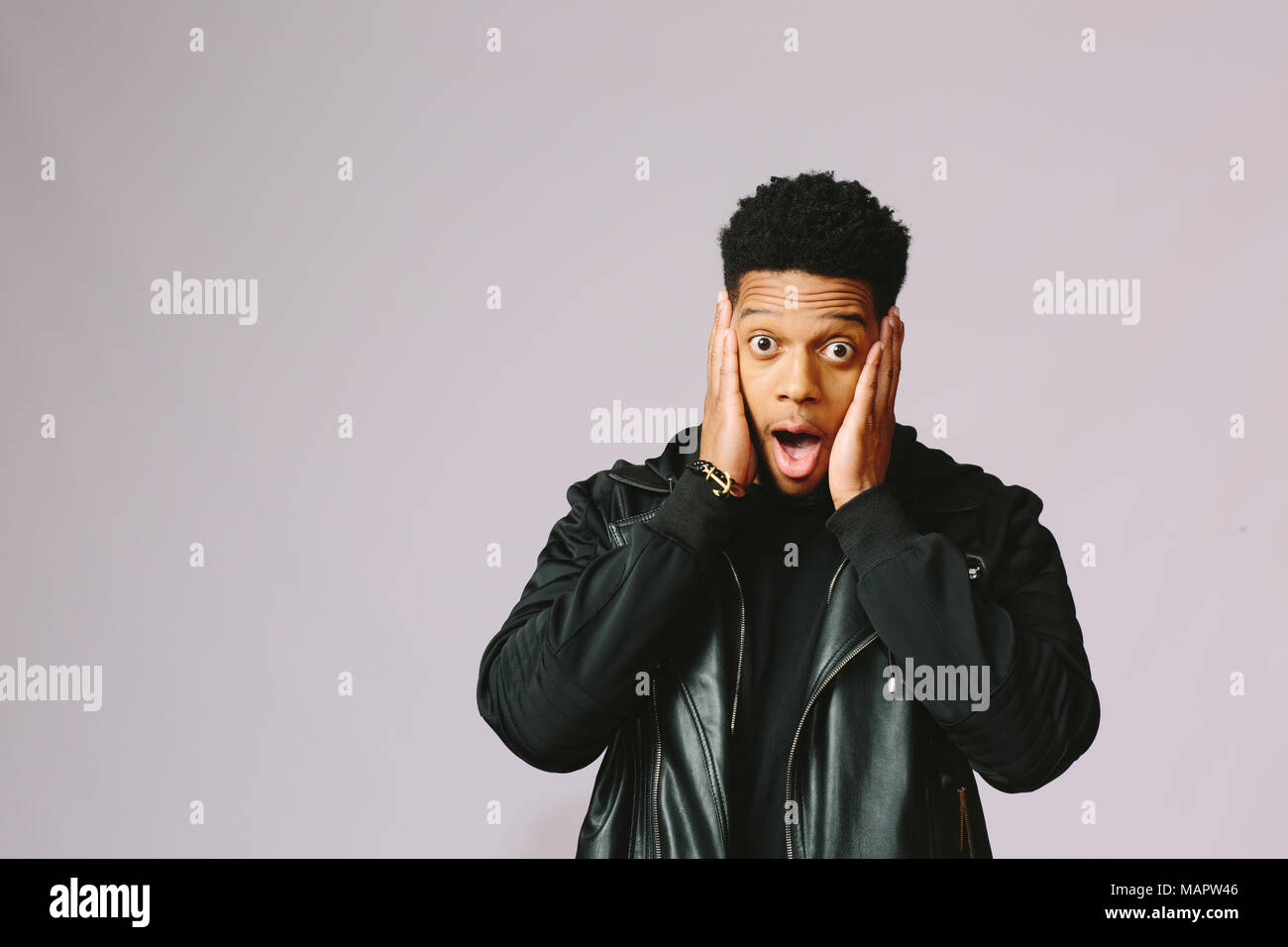 Portrait of a cool young man covering his ears with both hands, isolated on studio background Stock Photo
